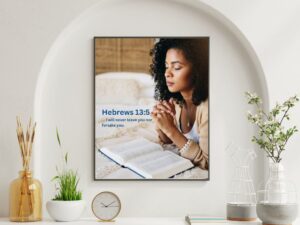 Never Alone Christian prayer wall art featuring an African-American woman praying with an open Bible, inspired by Hebrews 13:5.